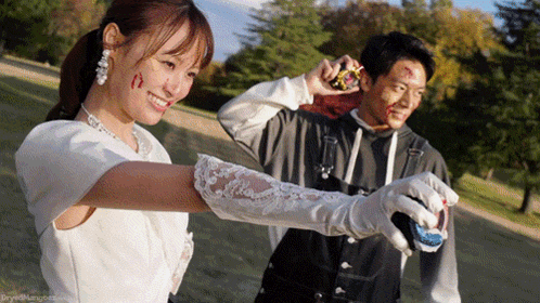 a woman in a wedding dress is standing next to a man with blood on his face holding a gun