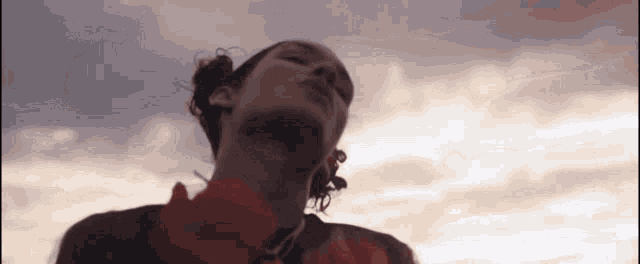 a close up of a woman 's face with a cloudy sky in the background