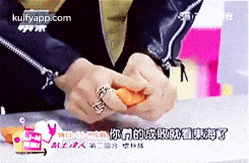 a person with a ring on their finger is peeling an orange .