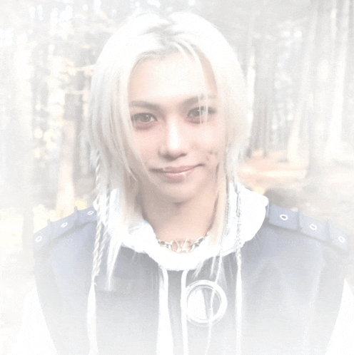 a young man with long white hair is wearing a blue jacket .