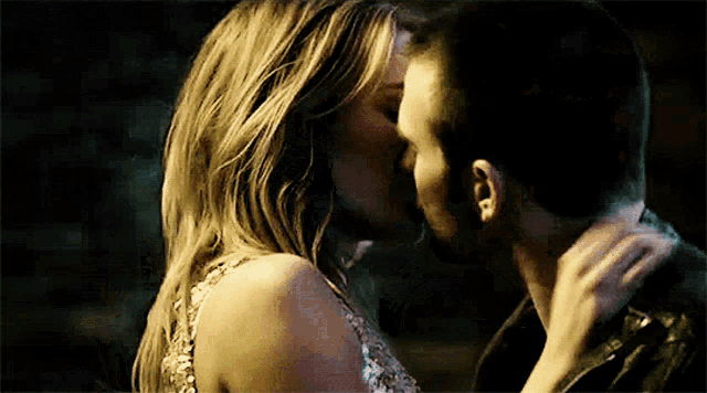a man and a woman are kissing in a dark room .