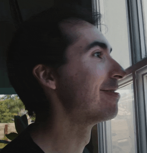 a man looking out a window with a smile on his face