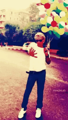 a man holding a bunch of colorful balloons with visagel.dz written on the bottom right