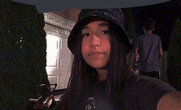 a girl wearing a bucket hat takes a picture of herself