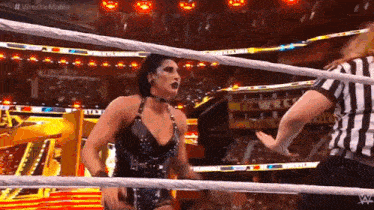 a woman is in a wrestling ring with a referee .