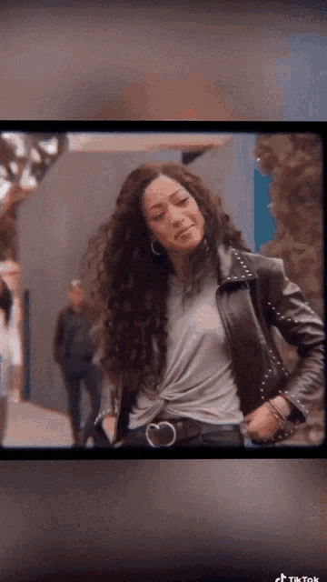 a woman with curly hair wearing a leather jacket