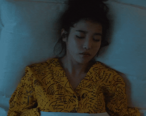 a woman laying in bed wearing a yellow shirt that says ' mango ' on the front