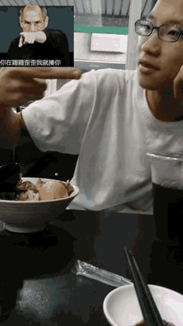 a person sitting at a table with a bowl of food and a picture of steve jobs