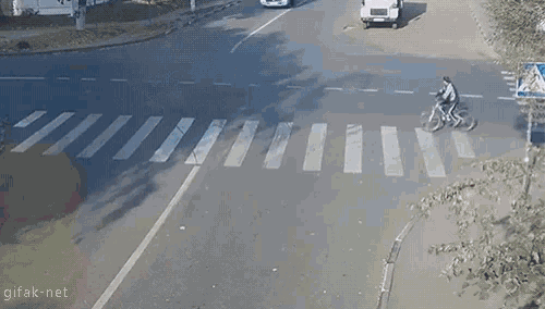 a man is riding a bike across a crosswalk while a truck is driving behind him