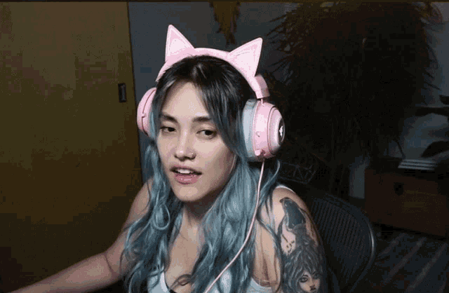 a woman with blue hair is wearing a pair of pink headphones