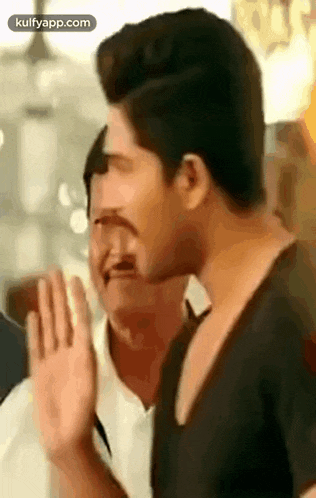 a man with a mustache is making a funny face while waving his hand .