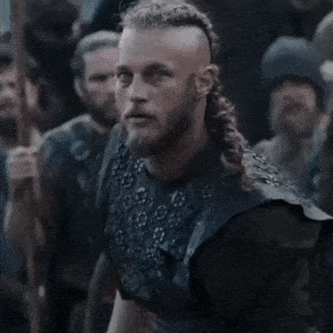 a man with a beard and long hair is standing in front of a crowd of people