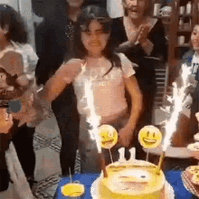 a group of people are standing around a birthday cake with candles .
