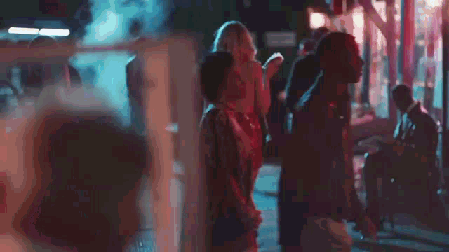 a woman is walking down a street at night