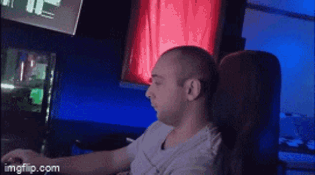 a man is sitting in a chair with his head resting on his arm while using a computer .
