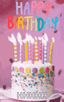 a birthday cake with candles and sprinkles on it is on a table .