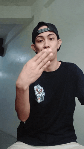 a man wearing a black shirt with a skull on it covering his mouth