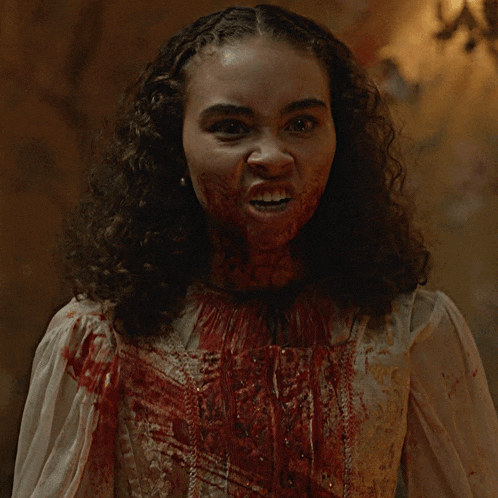 a woman with blood on her face is wearing a white top