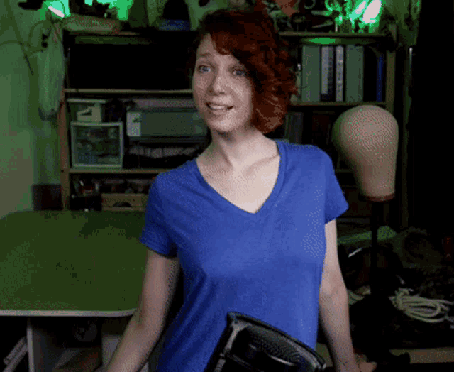 a woman in a blue shirt holds an iron