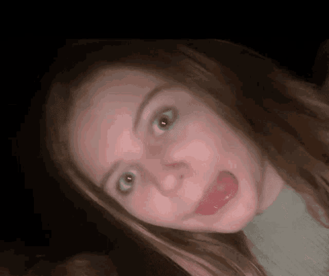 a close up of a girl making a funny face with her tongue sticking out .