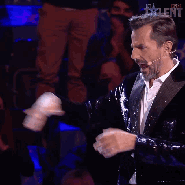 a man in a tuxedo stands in front of a crowd with the word talent on the bottom right