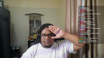 a man wearing headphones and glasses holds up his hand in front of a screen with a bunch of text on it