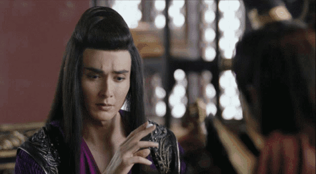 a man with long black hair is talking to another person