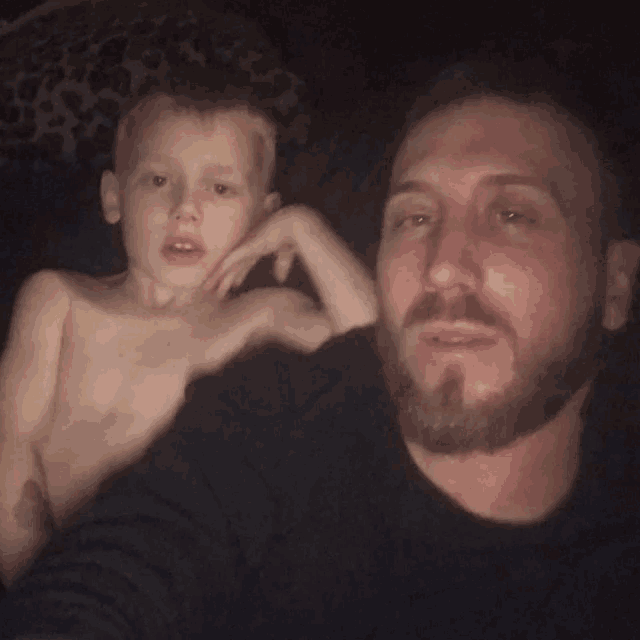 a man with a beard is sitting next to a young boy