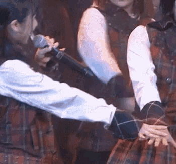 a woman is holding a microphone while another woman holds her arm around her .