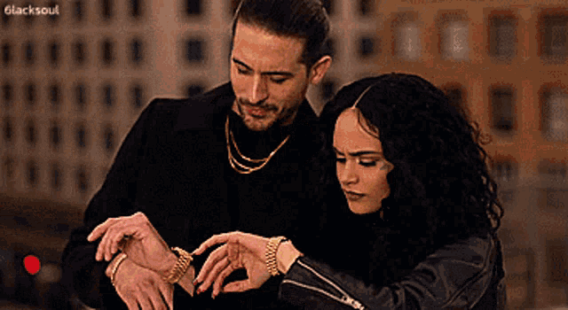 a man and a woman are looking at each other 's wristwatches with the words " blacksoul " in the corner