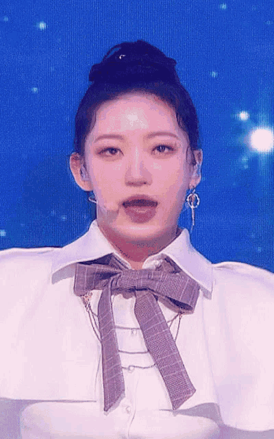 a woman wearing a white shirt with a bow tie and earrings