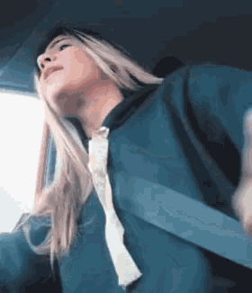 a woman wearing a blue hoodie and a seat belt