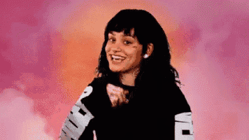 a woman wearing a black shirt with the word puma on the sleeves is smiling and pointing at the camera .