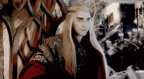 a man with long blonde hair is wearing a crown