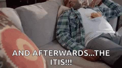 a man in a plaid shirt is laying on a couch with a cup of coffee on his chest .