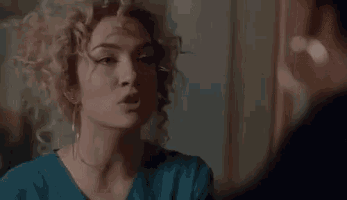 a woman with curly hair and earrings is talking to a man .