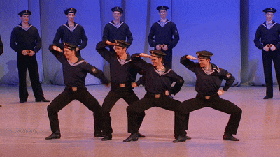 a group of men in navy uniforms are performing a dance