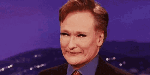 a man in a suit and tie is making a funny face while wearing fake eyelashes .
