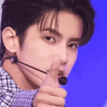 a close up of a person wearing a microphone giving a thumbs up .