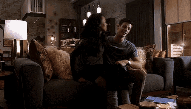 a woman is sitting on a man 's lap on a couch in a living room .