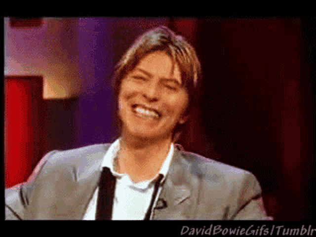 a man in a suit and tie is laughing and smiling
