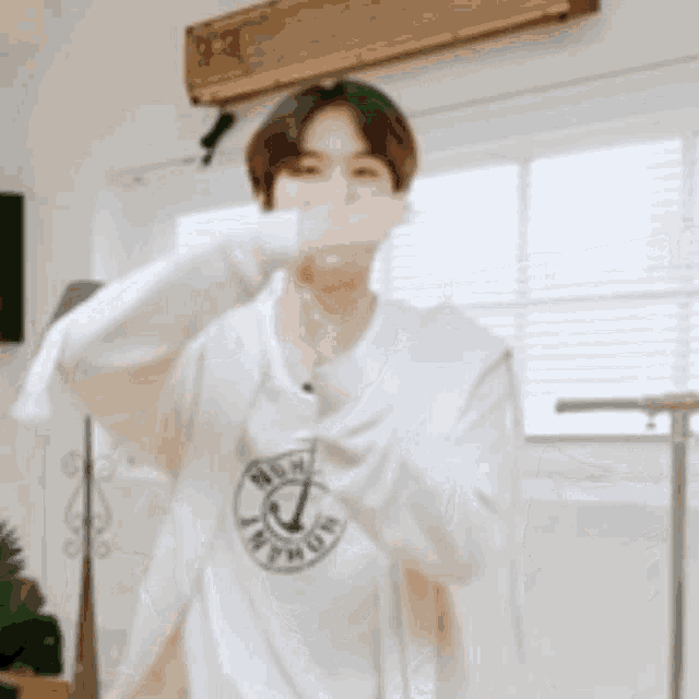 a young man wearing a white shirt with an anchor on it is dancing in a living room .