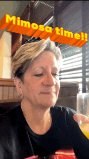 a woman sitting in front of a sign that says mimosa time !