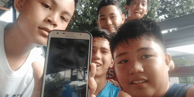 a group of young men are posing for a picture with a samsung cell phone