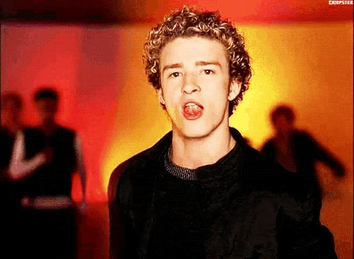 a young man with curly hair is singing into the camera .