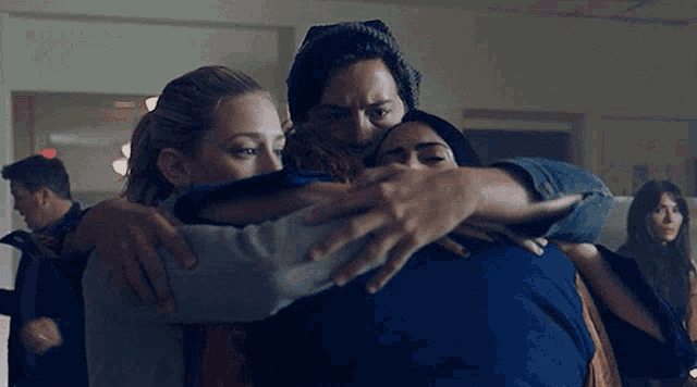 a group of people are hugging each other in a room in a crowded room .