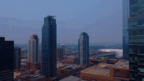 an aerial view of a city with a few tall buildings in the foreground and a stadium in the background
