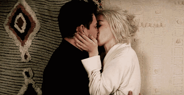 a man and a woman are kissing in front of a rug that says ' arique '