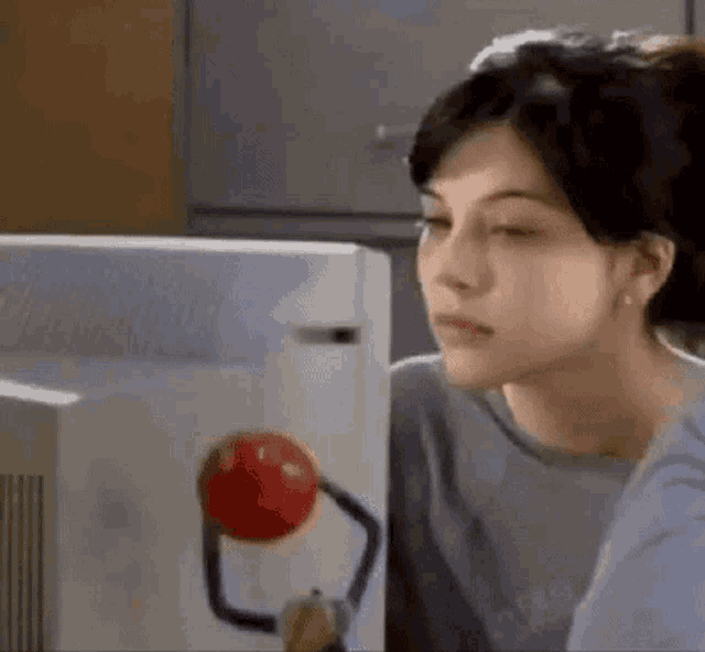 a woman is sitting in front of a computer monitor looking at a red ball .