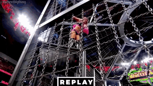 a woman is hanging from a chain in a cage with the word replay in the corner